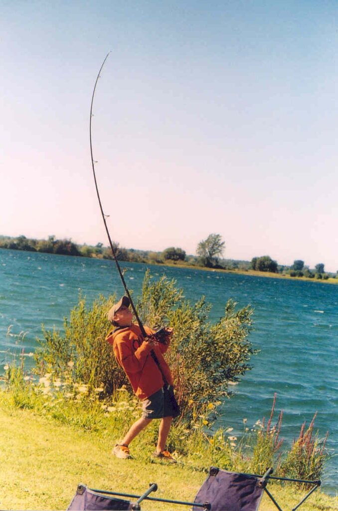Ein Angler beim Karpfenangeln am Ufer eines Sees